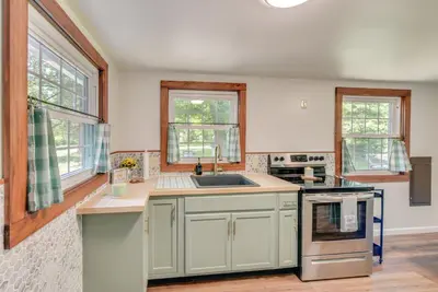a kitchen with white cabinets and a sink and windows at Peaceful Hiram Retreat on Cuyahoga River! in Aurora