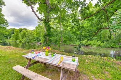 a picnic table in the grass next to a river at Peaceful Hiram Retreat on Cuyahoga River! in Aurora