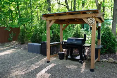a barbecue grill under a wooden pavilion in a garden at Mohican Hideaway in Brinkhaven