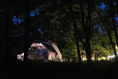 a tent sitting in the grass under trees at night at Mohican Hideaway in Brinkhaven