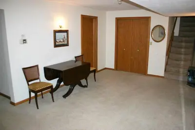 a living room with a piano and chairs and stairs at Portage Lakes Serenity in Akron