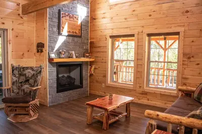 a living room with a fireplace in a log cabin at Hickory Ridge Cabin+Fire pit in Ewing