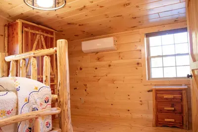 a log cabin bedroom with a bunk bed and a window at Hickory Ridge Cabin+Fire pit in Ewing