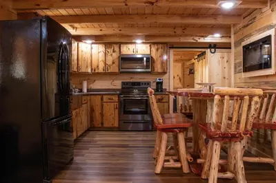 a kitchen with a black refrigerator and wooden cabinets at Hickory Ridge Cabin+Fire pit in Ewing