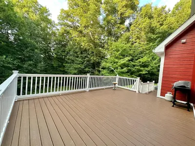 a deck with a white fence and a red house at Redbud Retreat in Centerville