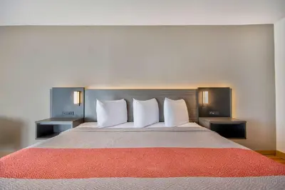 a large bed in a hotel room with white pillows at Motel 6 Walton, KY - Richwood - Cincinnati Airport South in Walton