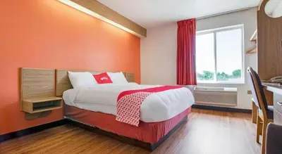 a bedroom with a large bed with an orange wall at Hotel Markle IN I-69 in Markle