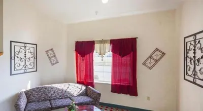 a room with a couch and a window with red curtains at Hotel Markle IN I-69 in Markle