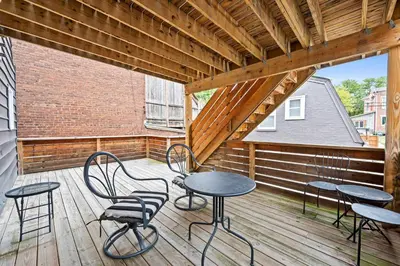 a patio with tables and chairs on a wooden deck at 1BR - Walk to Convention Center & Stadiums in Ludlow