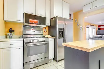 a kitchen with white cabinets and a stainless steel refrigerator at Great Lake Erie Getaway with Hot Tub and Private Beach in Avalon Beach