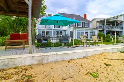 a patio with chairs and a table with an umbrella at Great Lake Erie Getaway with Hot Tub and Private Beach in Avalon Beach