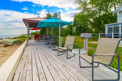 a group of chairs and an umbrella on a deck at Great Lake Erie Getaway with Hot Tub and Private Beach in Avalon Beach