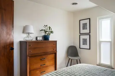 a bedroom with a dresser and a lamp and a chair at 4 Bed 3 bath Boutique Home Near OSU, Crew Stadium, Short North, COSI, & Downtown in Columbus