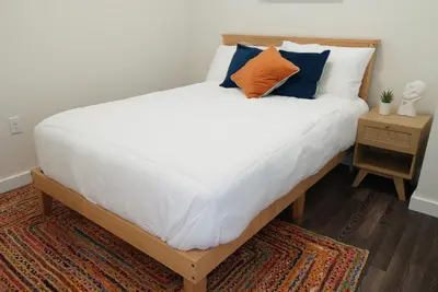 a bed with white sheets and an orange and blue pillow at The Standard Downtown Columbus in Columbus