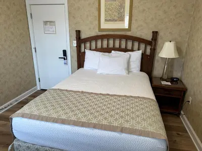 a bed with white pillows and a table with a lamp at Island House Historic Vacation Rentals in Port Clinton