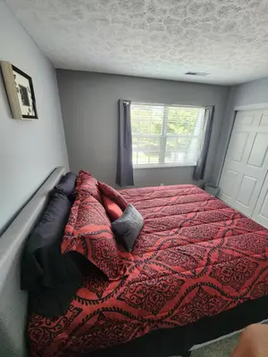 a bedroom with a bed with a red blanket and a window at FC Suites in Cincinnati