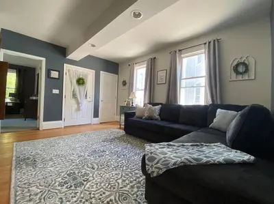 a living room with a blue couch and a rug at Cozy Main Street Flat in Adrian