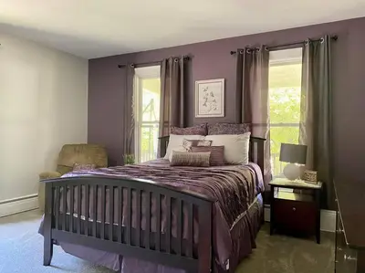 a purple bedroom with a bed and a chair at Cozy Main Street Flat in Adrian