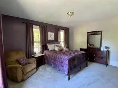 a bedroom with a bed and a chair and a mirror at Cozy Main Street Flat in Adrian