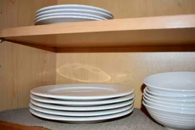 a stack of plates and bowls on a shelf at Cozy Garden House in Adrian