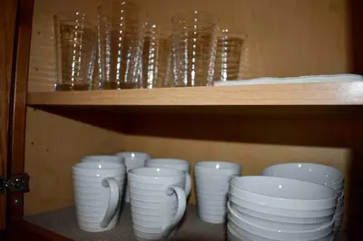 a row of white bowls and cups on a shelf at Cozy Garden House in Adrian