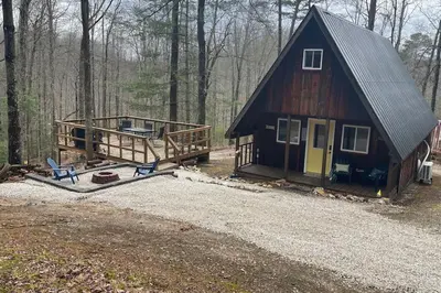 a cabin in the woods with two chairs and a house at HOT TUB -Secluded Cabin Cave Run Lake and near Red River Gorge in Wellington
