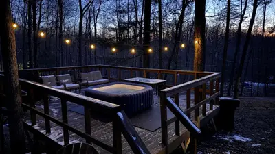 a deck with a hot tub and lights in the woods at HOT TUB -Secluded Cabin Cave Run Lake and near Red River Gorge in Wellington