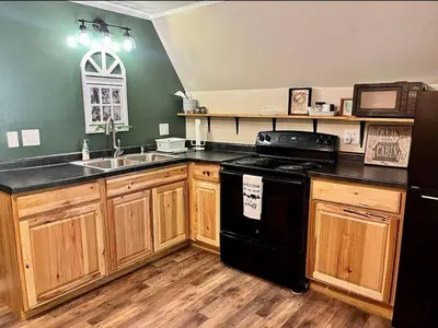 a kitchen with a black refrigerator and wooden cabinets at HOT TUB -Secluded Cabin Cave Run Lake and near Red River Gorge in Wellington