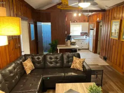 a living room with a leather couch and a kitchen at Take me to the River! in Zanesville
