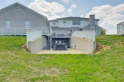 a house on top of a hill with a yard at Sprawling Kentucky Getaway with Pool and Hot Tub! in Berry
