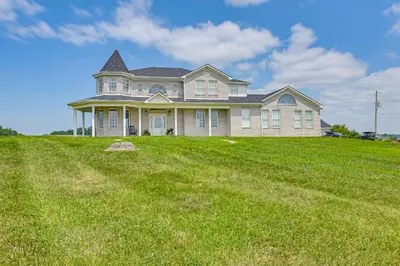 a house on top of a grassy hill at Sprawling Kentucky Getaway with Pool and Hot Tub! in Berry