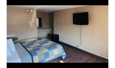 a bedroom with a bed and a tv on the wall at Hallmark Inn By OYO Fort Wayne in Fort Wayne