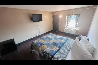 a bedroom with a bed and a tv on the wall at Hallmark Inn By OYO Fort Wayne in Fort Wayne