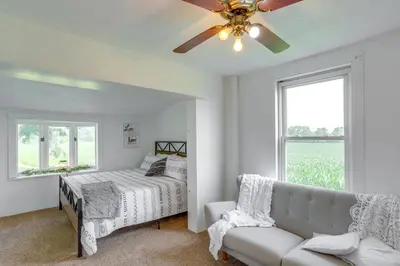 a bedroom with a bed and a couch and a ceiling fan at Ohio Farmhouse Retreat with Fire Pit and Patio in Monroeville
