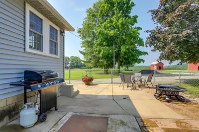 a backyard with a grill and a table and chairs at Ohio Farmhouse Retreat with Fire Pit and Patio in Monroeville