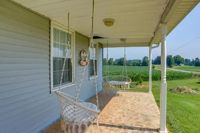 a porch swing on the side of a house at Ohio Farmhouse Retreat with Fire Pit and Patio in Monroeville
