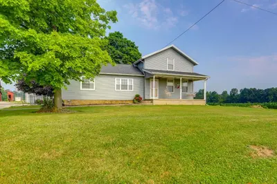 a house with a large yard with a tree at Ohio Farmhouse Retreat with Fire Pit and Patio in Monroeville