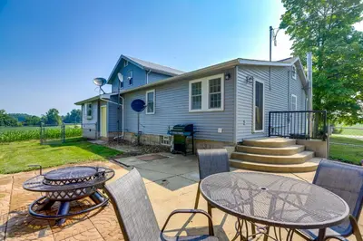 a patio with a table and chairs and a house at Ohio Farmhouse Retreat with Fire Pit and Patio in Monroeville