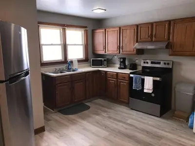a kitchen with wooden cabinets and a black refrigerator at 3BR 1BA North End Walk to the Hospital in Zanesville