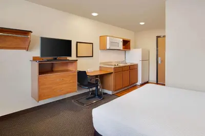 a hotel room with a bed and a desk with a television at WoodSpring Suites Columbus North I-270 in Columbus