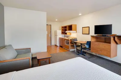 a hotel room with a bed and a living room at WoodSpring Suites Columbus North I-270 in Columbus