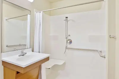 a white bathroom with a sink and a shower at WoodSpring Suites Columbus North I-270 in Columbus
