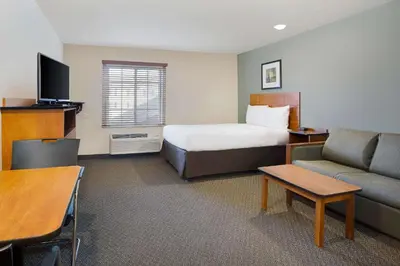 a hotel room with a bed and a couch at WoodSpring Suites Columbus North I-270 in Columbus