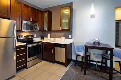 a kitchen with wooden cabinets and a table and a refrigerator at Residence Inn by Marriott Columbus Dublin in Dublin