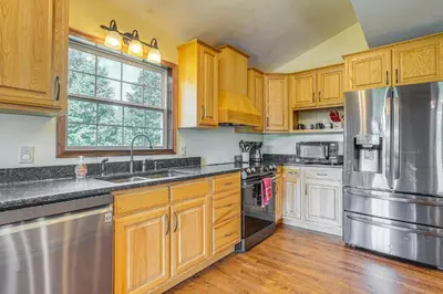 a kitchen with wooden cabinets and a stainless steel refrigerator at Quiet Family Cabin in Hamden Hot Tub and Game Room! in Hamden