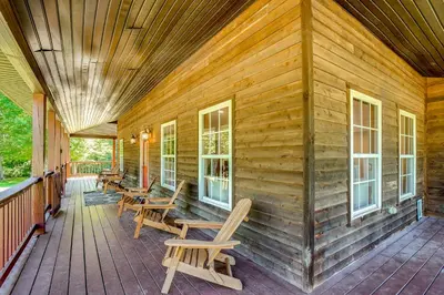 a wooden cabin with rocking chairs on the porch at Quiet Family Cabin in Hamden Hot Tub and Game Room! in Hamden