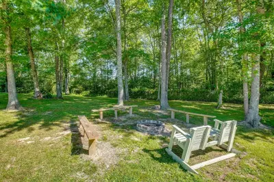 two chairs and a bench in a park with trees at Quiet Family Cabin in Hamden Hot Tub and Game Room! in Hamden
