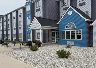 a blue building with benches in front of it at BlissPoint Inn & Suites, Northwood in Northwood