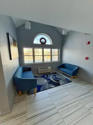 a living room with two blue chairs and a rug at BlissPoint Inn & Suites, Northwood in Northwood