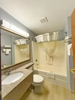 a bathroom with a sink and a toilet and a mirror at BlissPoint Inn & Suites, Northwood in Northwood